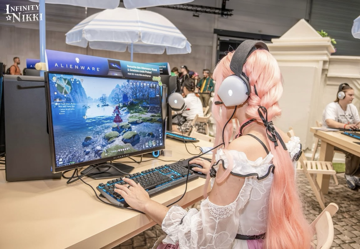 Cosplayerin spielt am Gaming-Setup auf einem Messestand der gamescom Köln